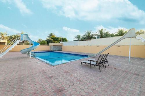 a swimming pool with a slide next to a building at Best chalet 4 BHK for group gatherings with beach access and private pool in Fujairah