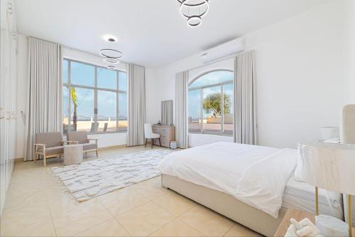 a white bedroom with a bed and a table and chairs at Best chalet 4 BHK for group gatherings with beach access and private pool in Fujairah