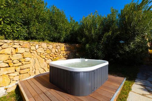 a bath tub sitting on a deck next to a stone wall at MH Suites in Olbia