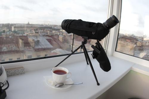 una cámara en un trípode junto a una taza de café en Mansarda, en San Petersburgo