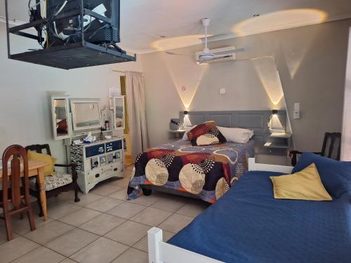 a bedroom with two beds and a table and a mirror at SMAPERS GUESTHOUSE in Brits