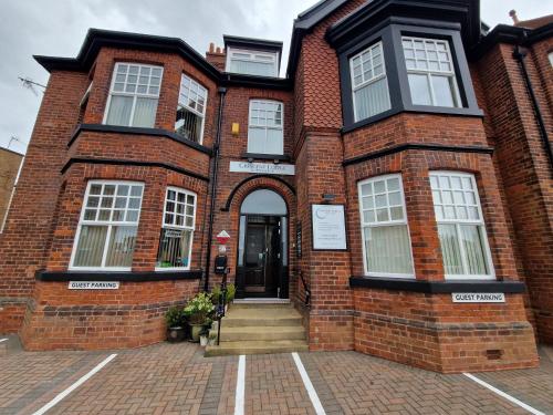 a brick building with a door and stairs in front at Crescent Lodge Guest House in Whitby