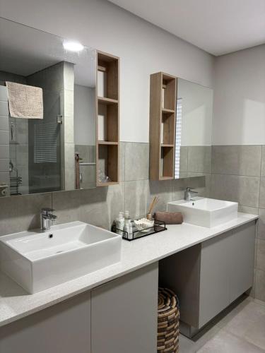 a bathroom with two sinks and a mirror at SixtyOneAt1- George Central in George