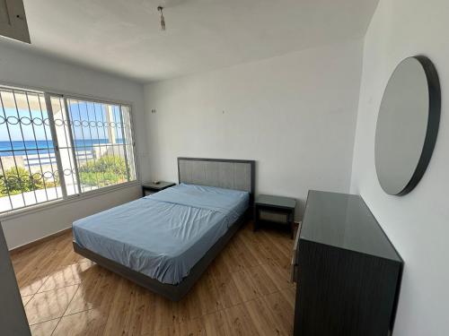 a bedroom with a bed and a table and windows at Villa Sounine Rafraf in Bizerte
