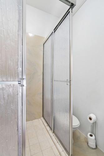 a glass shower door in a bathroom with a toilet at Arcadian Place in Port-of-Spain