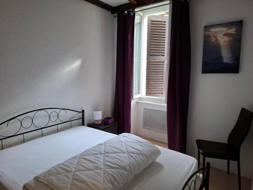 a bedroom with a bed and a window and a chair at AGREABLE APPARTEMENT in Eaux-Bonnes