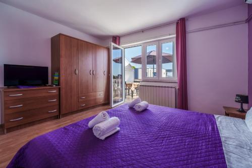 a bedroom with a purple bed with towels on it at Apartments Anka in Krk
