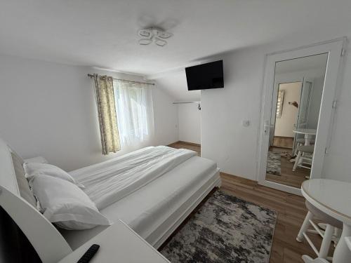a white bedroom with a large bed and a table at Lucatony's Guesthouse in Cîmpeni