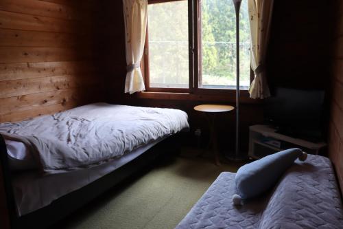 a bedroom with two beds and a window at Yamagata Zao Pension Apron Stage in Kaminoyama