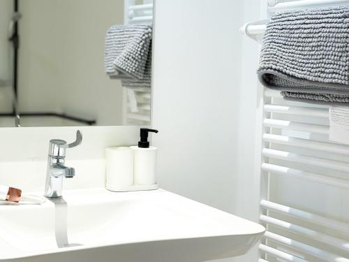 a white bathroom with a sink and a mirror at Volcania Suites in Clermont-Ferrand