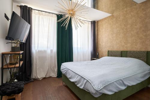 a bedroom with a bed with a television and a chandelier at Apartament Gold in Złotoryja
