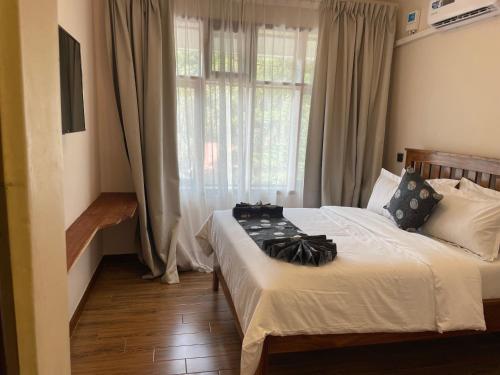 a bedroom with a bed and a window with curtains at Peak Park Hotel in Mbeya