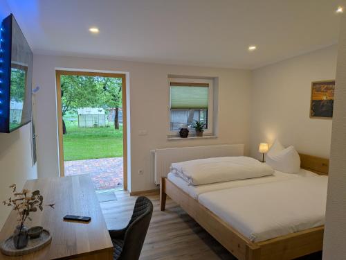 a bedroom with a bed and a table and a window at Landhotel Biberburg in Bad Liebenwerda