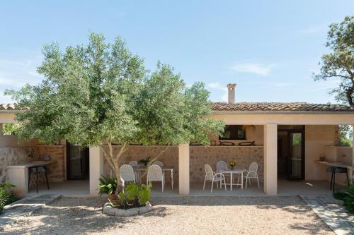a house with a tree and a table and chairs at Finca Son Vidal in Llucmajor