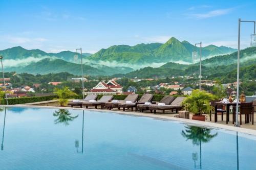 a hotel swimming pool with mountains in the background at Luang Prabang View Hotel in Luang Prabang