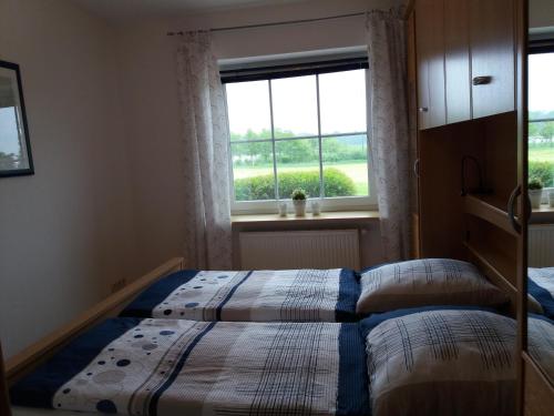 a bedroom with two beds in front of a window at FeWo am Pohlsee in Langwedel
