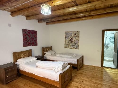 two beds in a room with wooden floors at Nurata mountains Hayat guesthouse in Yukary-Ukhum