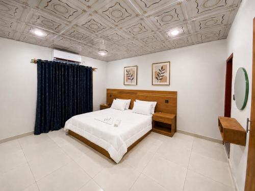 a bedroom with a large bed and a ceiling at Amada Family Guest House in Karachi