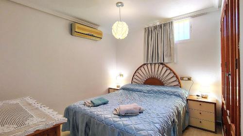 a bedroom with a bed with a blue comforter at Planta baja con piscina privada in Playas de Orihuela