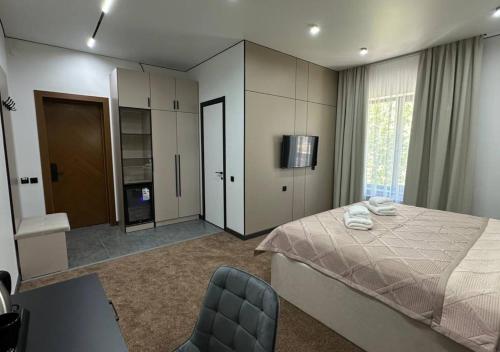 a bedroom with a bed and a tv and a chair at Park Avenue Hotel in Taraz