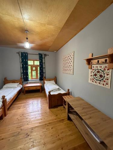 a room with two beds and a wooden floor at Nurata Eco Guesthouse in Yukary-Ukhum