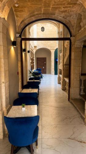 a row of tables with blue chairs in a hallway at Mulberry Suites by The LVH Collection in Valletta