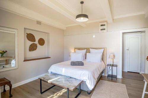 a bedroom with a white bed and a table at Sunny Cove Stays in Fish Hoek