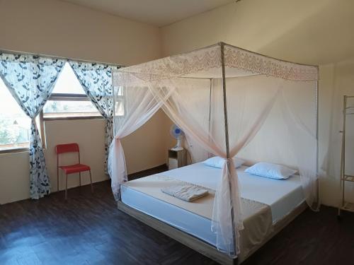 a bedroom with a canopy bed and a red chair at Purangjompa Homestay in Tiwuronto