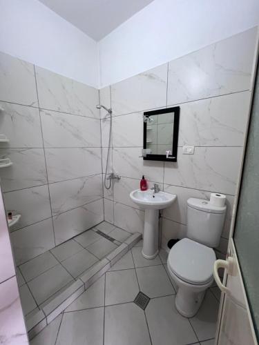 a white bathroom with a toilet and a sink at Vila Beliz in Tirana