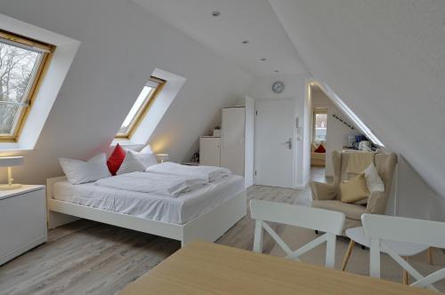 a white bedroom with a bed and a chair at Landhaus Dreesen in Timmendorfer Strand