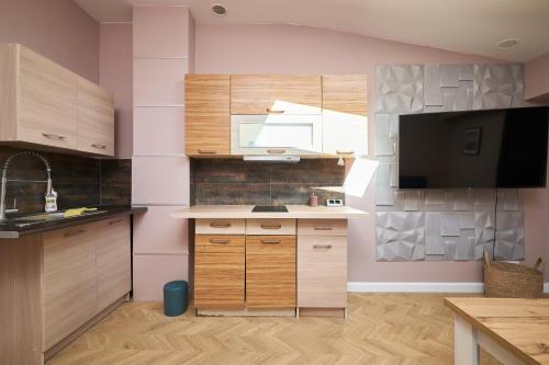 a kitchen with wooden cabinets and a tv in it at Apartamenty Zlotoryja Silver in Złotoryja