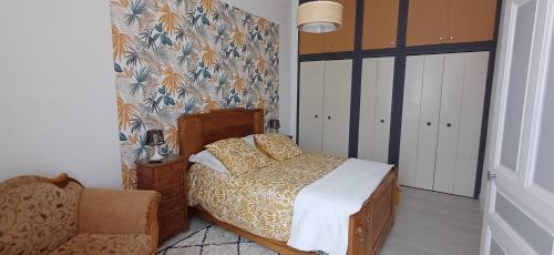 a bedroom with a bed and a chair at L escapade de la voie douce in Le Cheylard