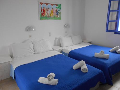 two beds in a room with towels on them at The Three anchors Rooms Perissa in Perissa