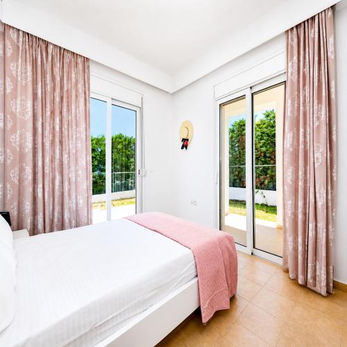a bedroom with a bed and large windows at Gennadi Villa Mare 300m from the Beach in Gennadi