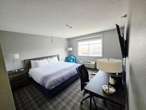 a hotel room with a bed and a desk with a desk at AmericInn by Wyndham Minot in Minot