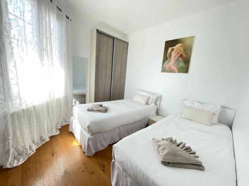 two beds in a room with white walls and a window at Bella Stay in Cannes