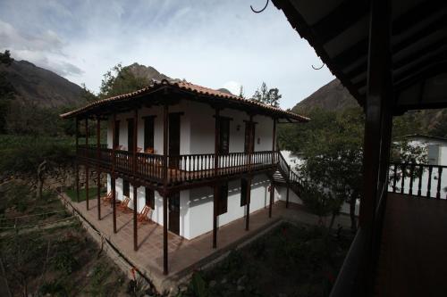 a small house with a balcony and a mountain at El Albergue Ollantaytambo in Ollantaytambo
