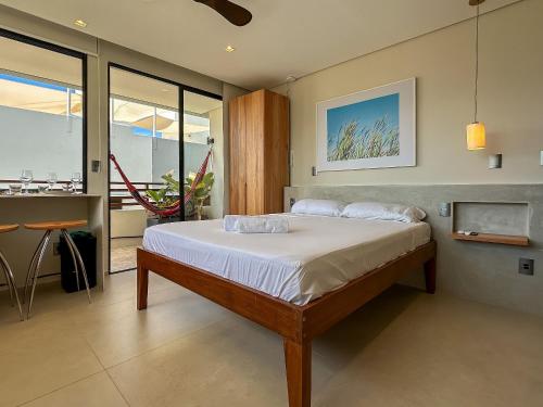 a bedroom with a bed and a table and some windows at Chalé by Vila Manga Rosa in Pipa
