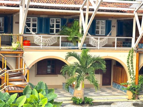 a building with a palm tree in front of it at Pousada Vila da Barra in Ilha de Boipeba