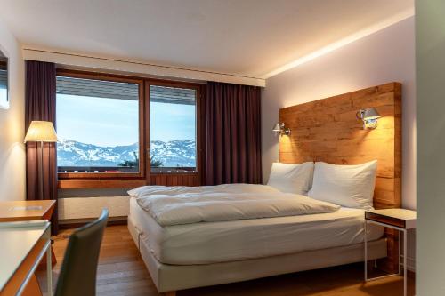 a hotel room with a bed and a desk and window at Wellness Hotel Stoos in Stoos