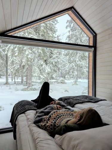 a woman laying on a couch in front of a window at Arctic Nest Forest Cabin in Kotila