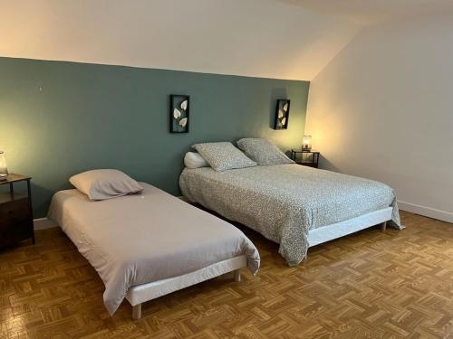 two beds in a bedroom with green walls at Maison de Village in Leuglay