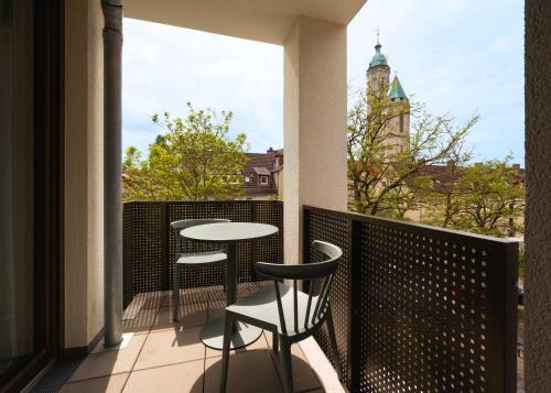 a balcony with a table and chairs and a view at Limehome Braunschweig Kaiserstraße in Braunschweig