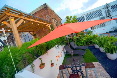 a patio with an umbrella and chairs and plants at 1.6 • Balcony • Generator • Parking • 2nd Floor in Mayaguez