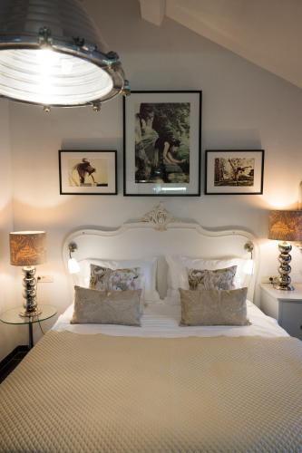 a bedroom with a white bed with pictures on the wall at Prijeko Palace in Dubrovnik