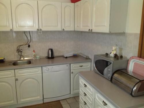 a kitchen with white cabinets and a sink and a microwave at Holiday Home Hodo in Sarajevo