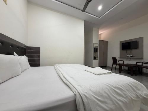 a large white bed in a room with a table at Hotel Velga in Kurukshetra