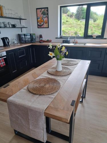 a wooden table in a kitchen with a vase of flowers on it at Muckish Hideaway in Crockglass