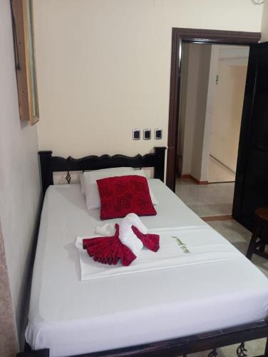 a white bed with a red blanket and towels on it at Hotel Las Golondrinas in Puerto Berrío