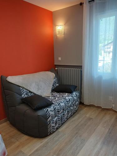 a black couch in a room with a window at Le Conty in Saint-Jorioz